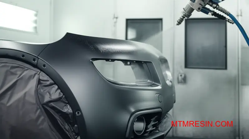 En robot sprøjter primer på en bildel af polypropylen, et vigtigt trin i overfladebehandlingen af tekniske polyolefinmaterialer.